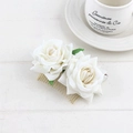 Detail of two white velvet faux roses with green leaves on a gold metal hair comb - Beige