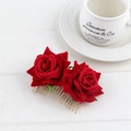 Détail d'un peigne à cheveux rose en velours rouge avec dents en métal doré sur bois blanc - Rouge