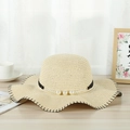 Detail of straw sun hat with decorative black band, pearls, and wavy scalloped edge trim - Beige