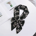 Elegant black skinny scarf with white floral patterns tied in a bow on a white table - Black White Magnolia