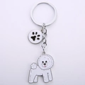 Detail eines süßen weißen Bichon-Hundeanhängers mit silbernem Clip und Pfotenabdruck - Bichon Frise Pfote