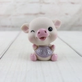 Detailansicht einer rosa Schweinchen-Figur aus Harz mit lila Latz und Aufschrift - Rosa Zwinkern - Gelassen
