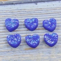 Macro shot of 12mm dark blue heart-shaped resin opal beads with glitter for DIY jewelry making - Blue