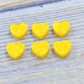 Macro shot of 12mm heart shaped yellow synthetic fire opal stones on wooden background - Yellow