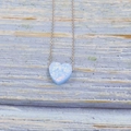 Minimalist silver necklace with heart-shaped blue opal pendant on a rustic wood background - Sky Blue