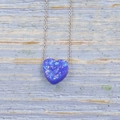 Makroaufnahme eines blauen Herz-Opal-Anhängers mit Regenbogen-Schimmer an Silberkette - Blau