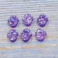 Sechs lila Hamsa-Hand-Anhänger aus Harz mit Glitzereffekt auf blauem Holzhintergrund - Handform Ohne Loch / Lila