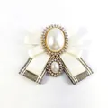 Elegant ivory ribbon bow brooch with pearl and rhinestone accents on white backdrop - White With Pin