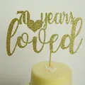Glittery gold cake topper with 70 years loved text and heart on a cream cake - 70 years loved