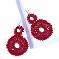 Detailed view of red beaded double hoop earrings handcrafted on white geometric blocks - Red
