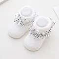 Detail of white infant socks with lace frill and polka dot bow on knitted fabric - 0-6 Months / White