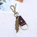 Porte-clés plume en bronze vintage avec lanière en cuir marron sur fond blanc - Marron