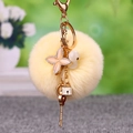 Light yellow faux fur pompom keychain with crystal flower and pearl charms on gold ring - Clover Key + Beige Pom Pom