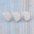 Detailed macro view of three white resin tiny foot-shaped beads with glitter finish - White