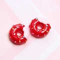 Detailed macro view of two red resin donuts with pink frosting and colorful sprinkles - Red