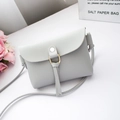Mini light grey-blue crossbody bag with flap and metal ring accent in a minimalist setting - Light Gray