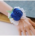 Detail of blue satin rose wrist corsage with white lace bow and pearls on a model wrist - Sapphire Blue