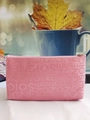 Detail of pink makeup bag with embossed SOIGNE letters and golden zipper close-up - Pink