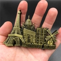 Close-up of bronze metal 3D fridge magnet featuring Paris landmarks held in hand - Large Paris Panorama