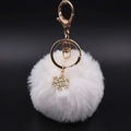 Detail van de witte pluche pompon sleutelhanger met gouden sneeuwvlok en karabijnhaak - Wit