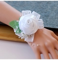 Detail der weißen Satinrose Armbandblume mit Perlen und grünen Blättern für die Hochzeit - Reinweiß