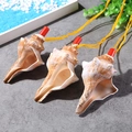 Three natural shell whistle pendants with red caps and yellow cords on a beach scene base - Red Swirl Shell Whistle