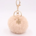 Detailed view of light pink fluffy pompom keychain with golden snowflake pendant and clasp - Nude