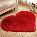 Plush heart-shaped red faux fur rug on light wood floor for cozy bedroom decor - Red