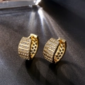 Makro-Detail von goldenen Huggie-Ohrringen mit Zirkonia und hexagonalen Ausschnitten - Gold