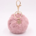 Detail view of a fluffy pink faux fur pompom keychain with a golden snowflake metal charm - Dusky Pink