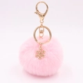 Detail of pink faux fur keychain with golden alloy snowflake pendant on soft background - Light Pink
