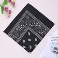 Classic black and white paisley cotton bandana displayed on a light wood background - Black