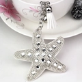 Macro detail of starfish keychain featuring white rhinestones and a silk tassel charm - White