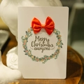 Kerstkaart met groene krans, oranje strik en vrolijke kerstwens op papier - Rode strik / Rood