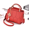 Red pebbled leather handbag with hexagonal stitching and gold geometric pendant charm - Red