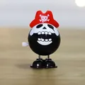 Wind-up pirate toy with black skull face and red hat on wooden background - Pirate with Hat