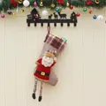 Rustic burlap Christmas stocking with Santa Claus doll and hanging gift boxes on wood wall - Santa Claus