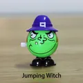 Wind-up green witch Halloween jumping toy with purple hat on wooden surface - Witch