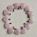 Pendenti a cuore in quarzo rosa con ganci metallici su sfondo in legno chiaro - Quarzo rosa