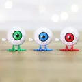 Wind-up jumping eyeball toys with veins in green, blue and red colors on wood surface - Eyeball
