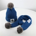 Dettaglio del set cappello e sciarpa in maglia blu e grigio con stella e pompon - Blu