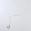 Detail shot of a polished silver oval pendant necklace with a beaded edge on white background - Oval