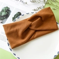 Detail of a brown twisted knit headband made of elastic ribbed fabric on a white plate - Coffee