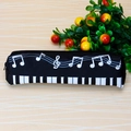 Close-up of black canvas pencil case with white piano keys and music notes patterns - Black