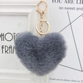 Close-up of a soft grey heart-shaped faux fur pom pom keychain with gold metal clip - Dark Gray
