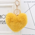Close-up of fluffy yellow heart plush keychain with golden metal clasp and chain - Turmeric