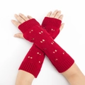 Close-up of red knitted arm warmers with heart pattern and thumb hole detail - Red