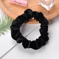 Detailed texture of a classic black velvet scrunchie on a decorative wooden tray - Black