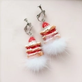 Close-up of strawberry cake earrings with red fruit and white fur ball dangles - Faux Fur Ball Clip