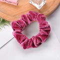 Close-up of elegant rose red velvet scrunchie with rich pleated texture on a wooden tray - Rose Red